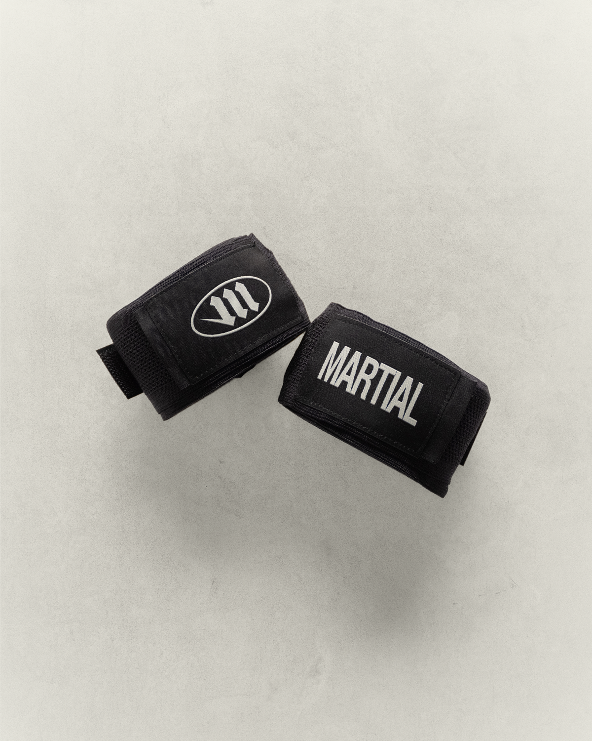 Two black martial arts or boxing hand wraps rolled up on a light gray background