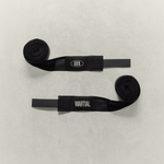 Two black martial arts or boxing hand wraps on a light gray background