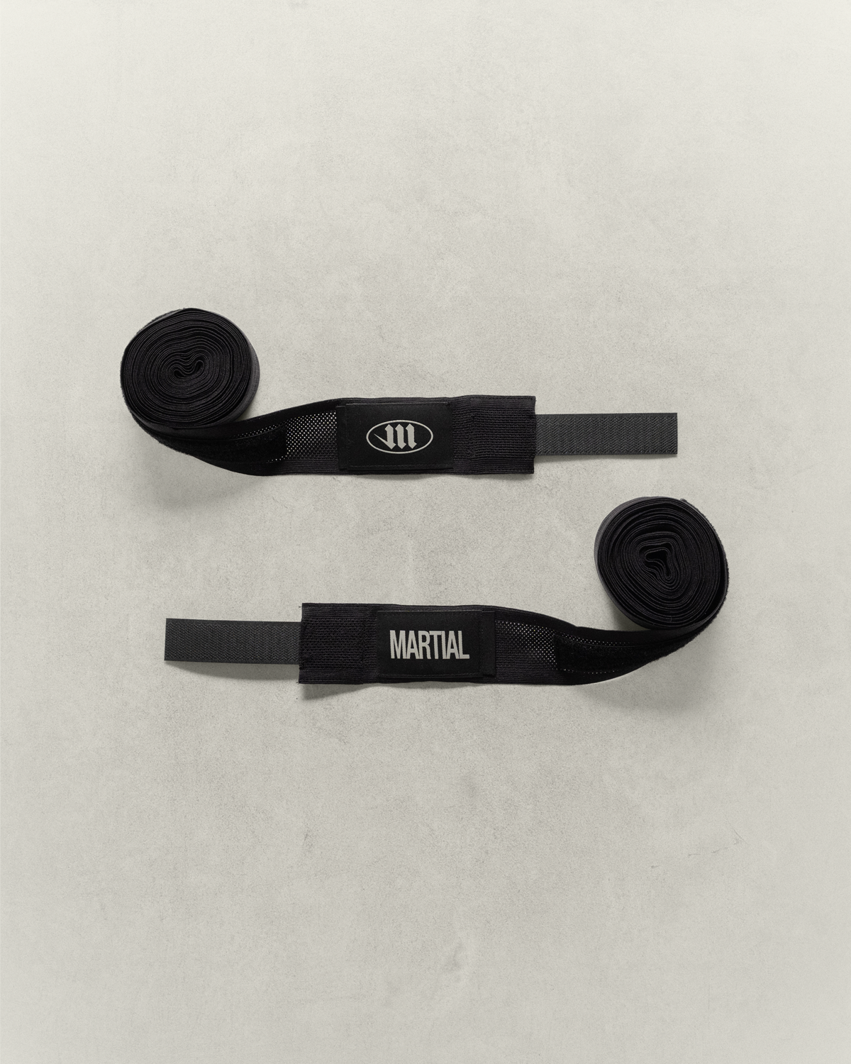 Two black martial arts or boxing hand wraps on a light gray background