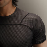 Up-close detail of black Martial rashguard on a man, standing in front of a gray background.