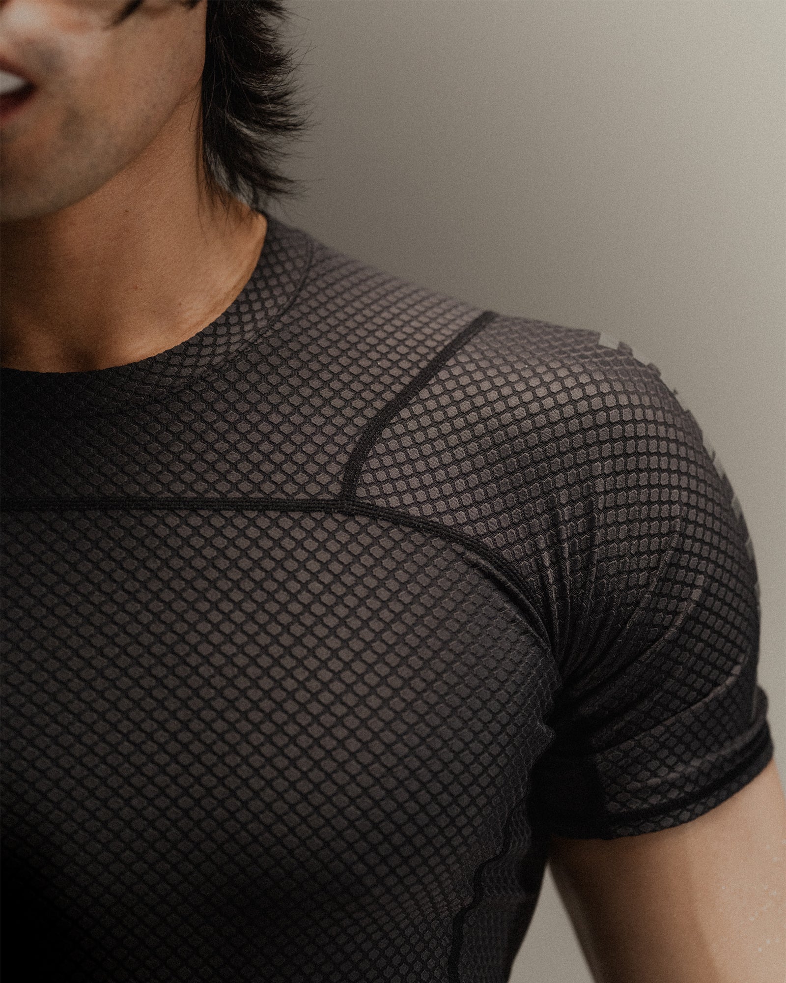 Up-close detail of black Martial rashguard on a man, standing in front of a gray background.