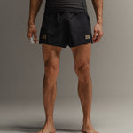 Man wearing black Martial fight shorts with gold accents on a neutral background