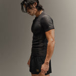 Man wearing black fight shorts and black Martial rashguard on a gray background