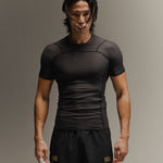 Man wearing black fight shorts and black Martial rashguard on a gray background