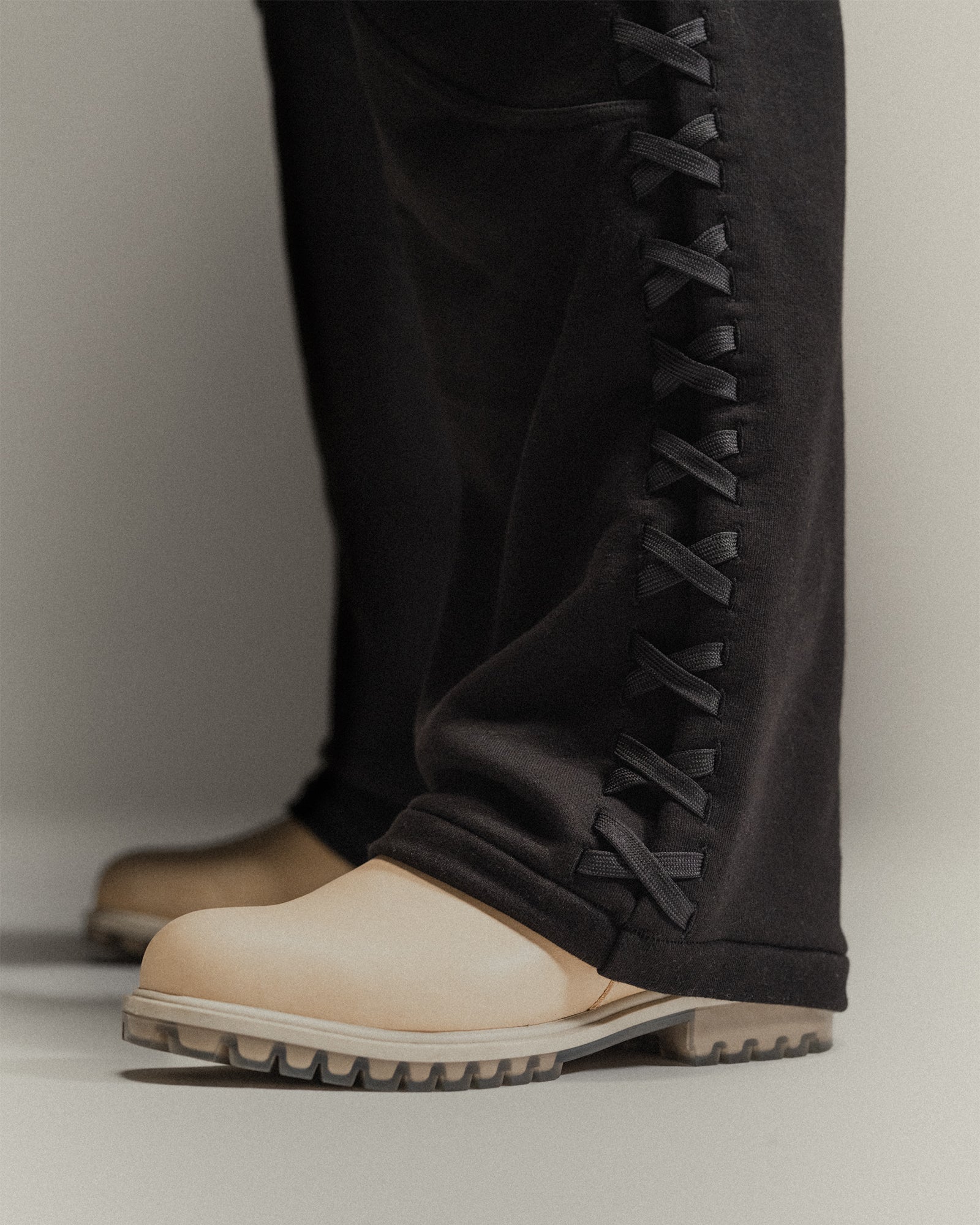 Close-up of lace weave detail on left leg of black 'Martial' sweat pants