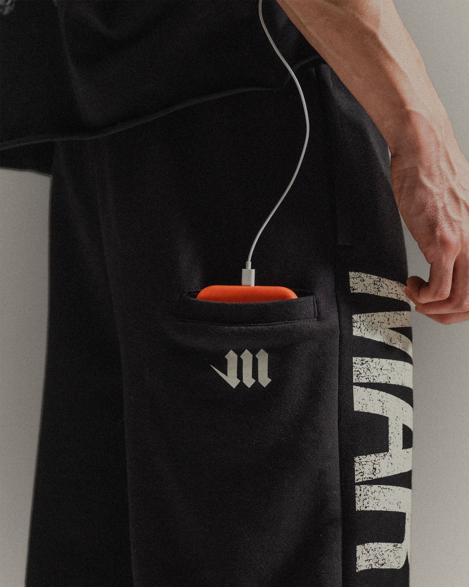 Up-close of side drop phone pocket on black 'Martial' sweatpants 