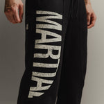 Up-close of black straight-leg sweat pants with 'Marital' graphic on a gray background