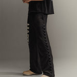 Man wearing black pants with lace-up sides on a gray background