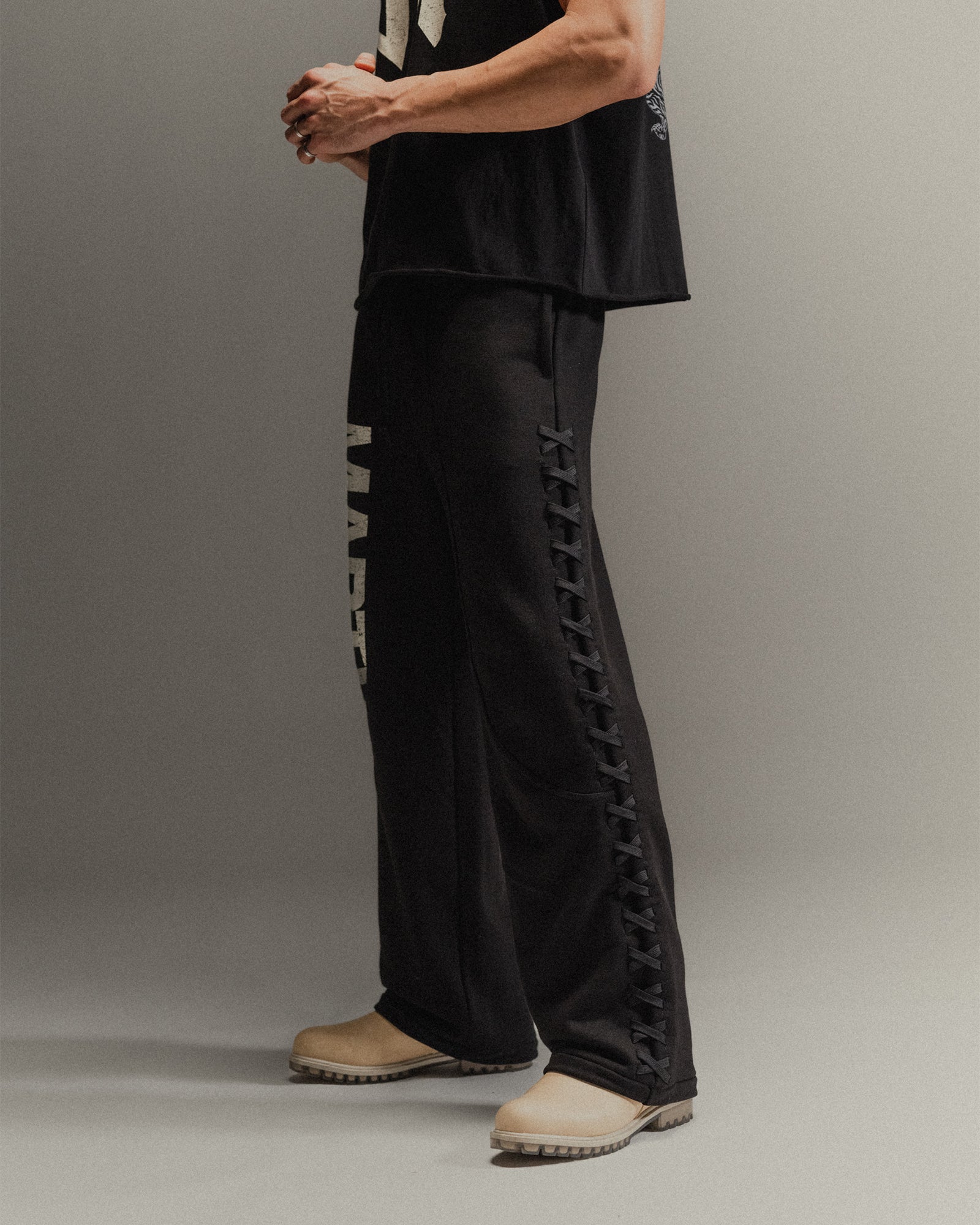 Man wearing black pants with lace-up sides on a gray background