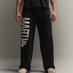 Man wearing black pants with 'Martial' graphic on a gray background