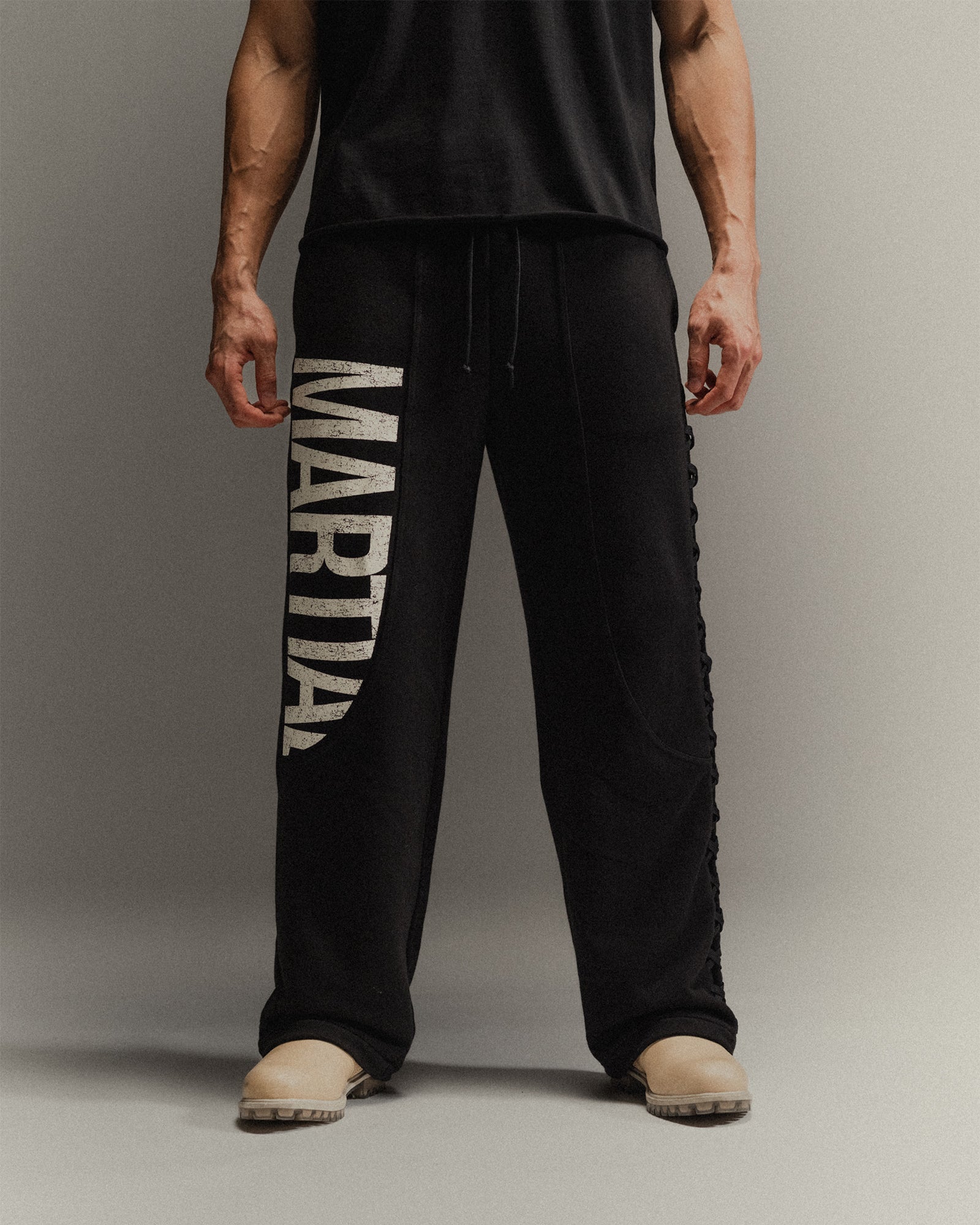 Man wearing black pants with 'Martial' graphic on a gray background