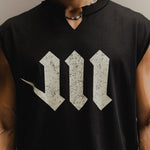 Man wearing a black sleeveless shirt with a white M logo on a neutral background