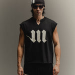 Man wearing black skullcap, sunglasses, black Martial cut-off shirt with a neck slit and cream logos, and black Martial sweats on a neutral backdrop.