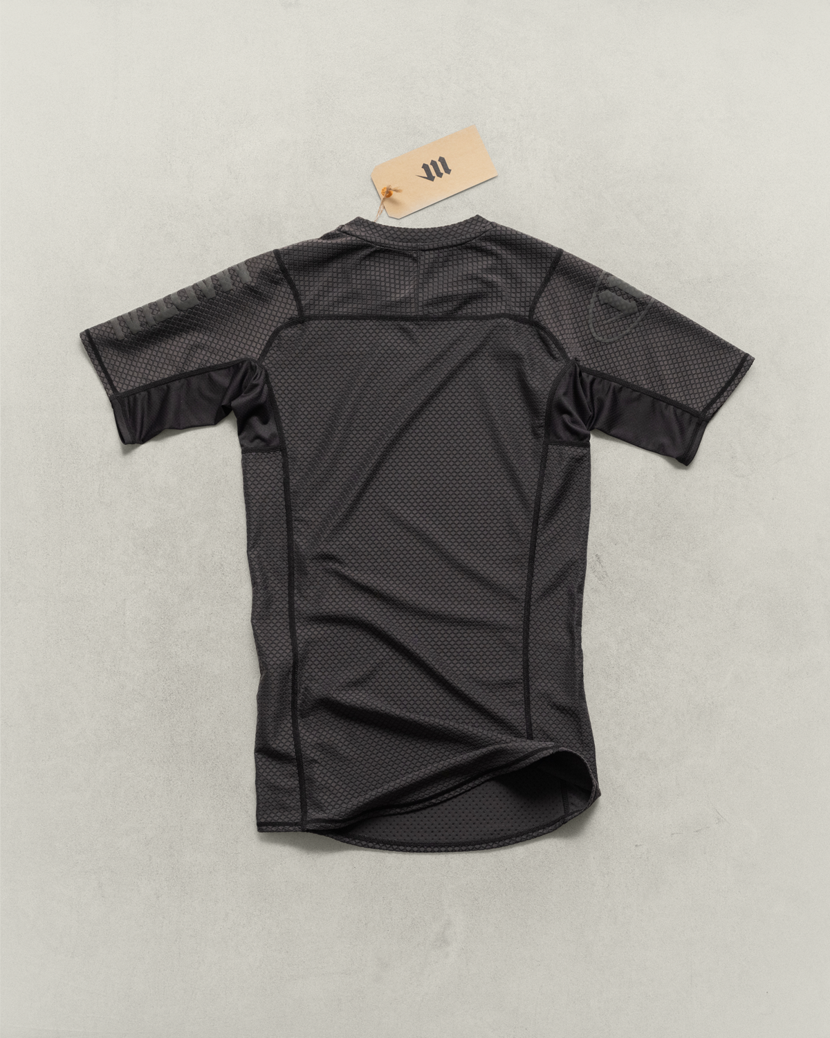 Black Martial rashguard laying face down on a neutral backdrop.