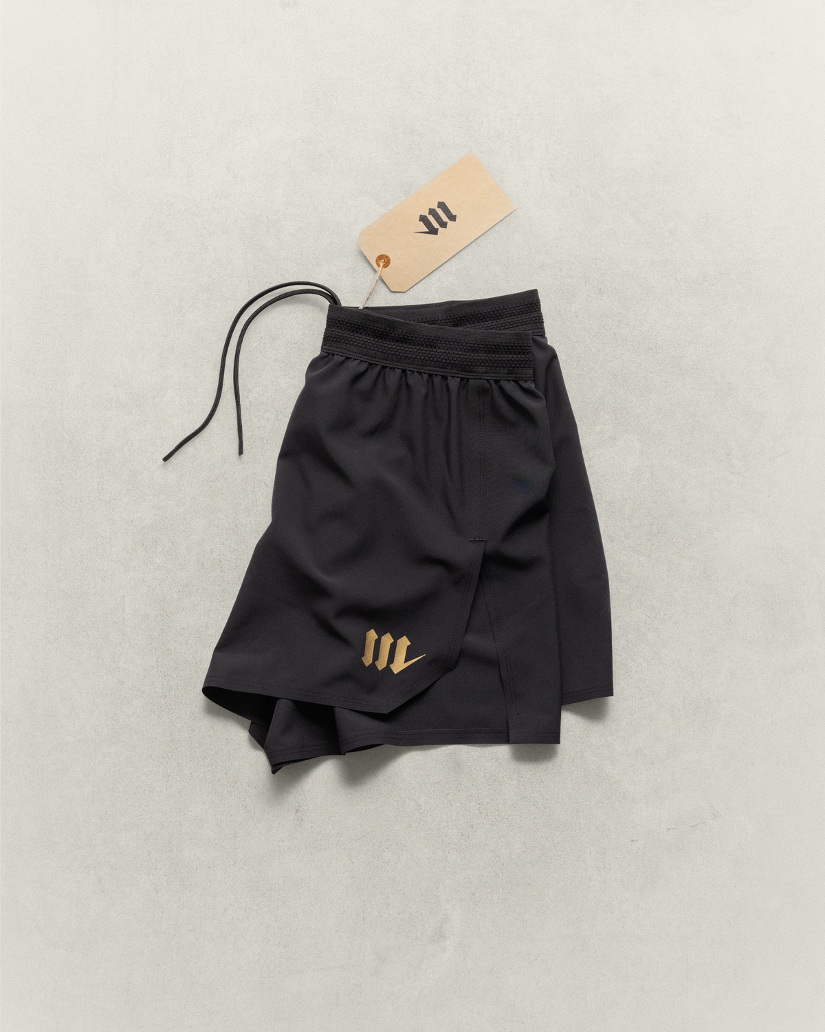 Black Martial fight shorts folded and laying on a neutral backdrop.