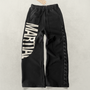 Black sweatpants with 'MARTIAL' text graphic and lace weave design laying on a light gray background