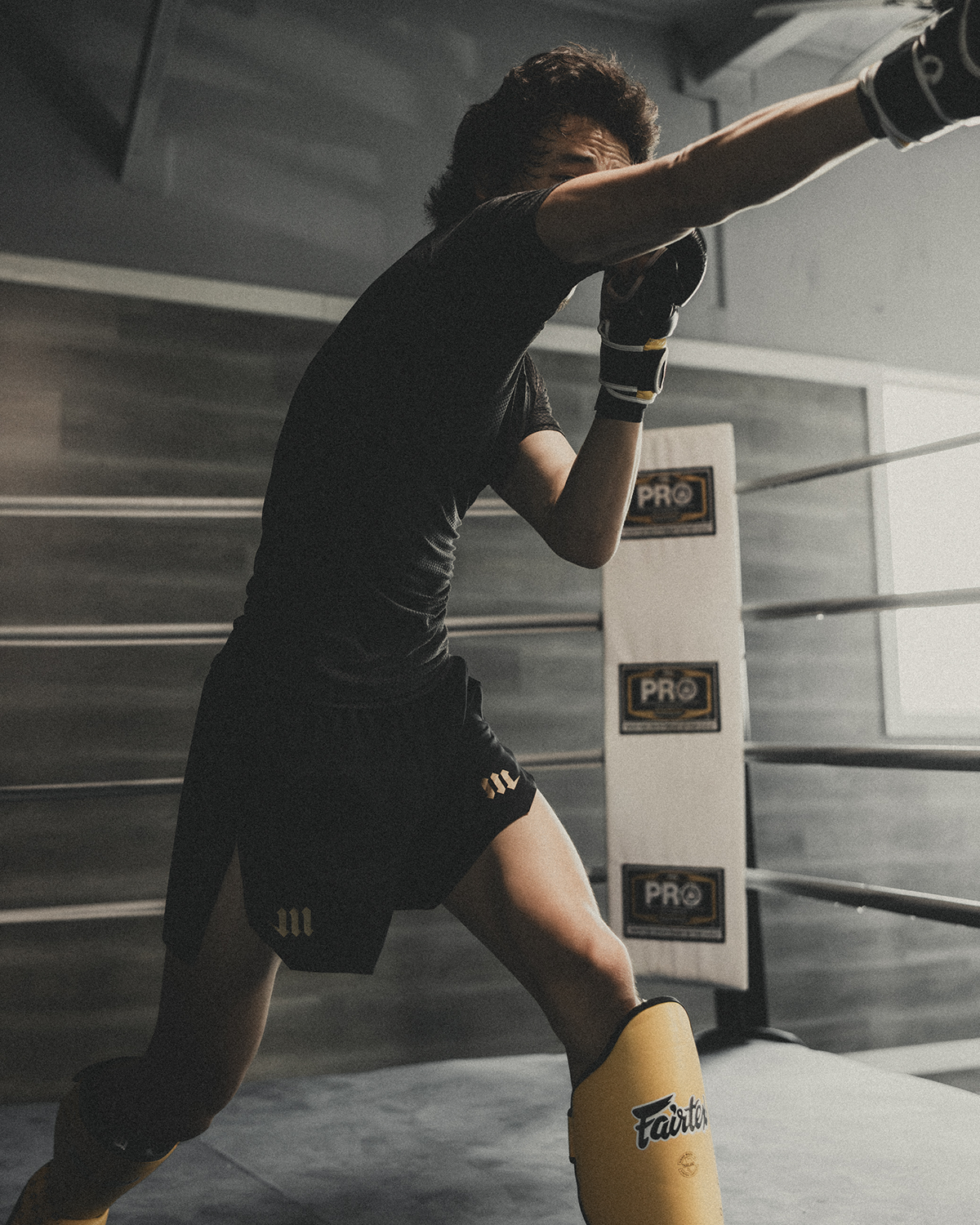 Man throwing punch in black rash guard and black fight shorts.